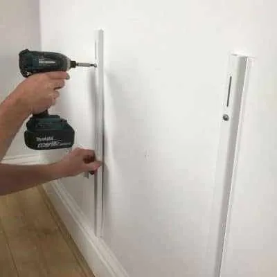 Installer drilling a wall bracket during a radiator fitting