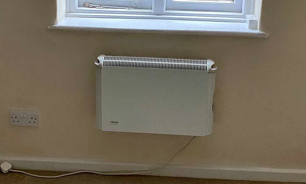 Old wall-mounted convector heater being replaced with a modern electric radiator