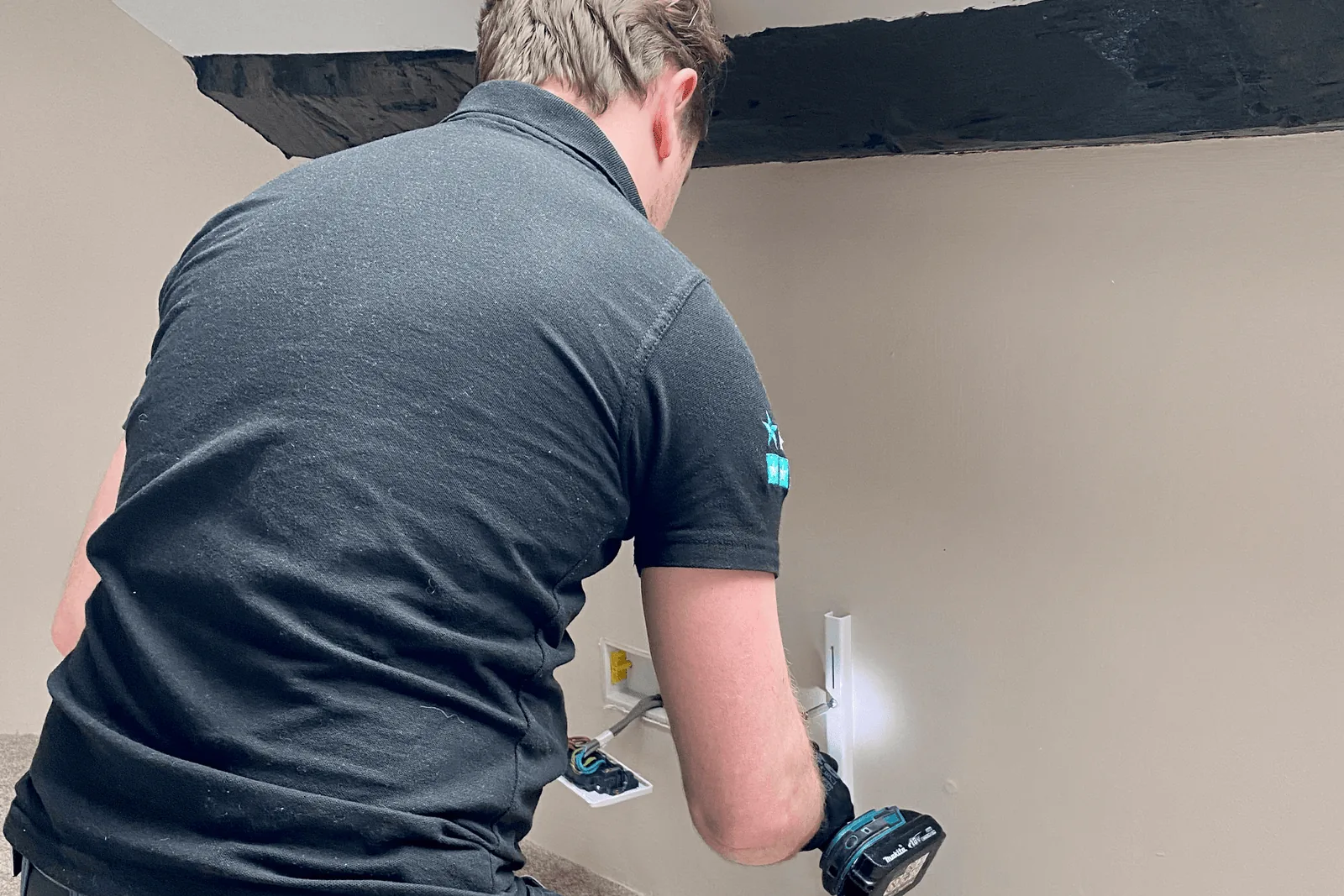 Engineer hard-wiring a wall-mounted electric radiator