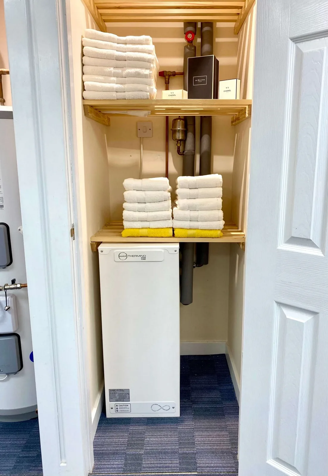 Compact heat battery installed in an airing cupboard below folded towels